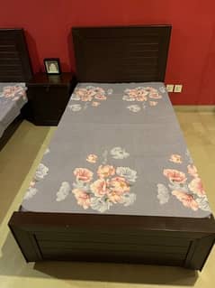 2 single beds with 1 side table and mattress