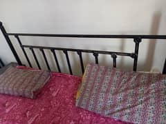 iron bed with mattress. two side tables as well.