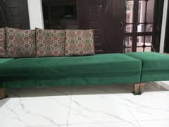 l shaped sofa in green color with cushions