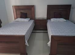 2 wooden single beds with 1 side table