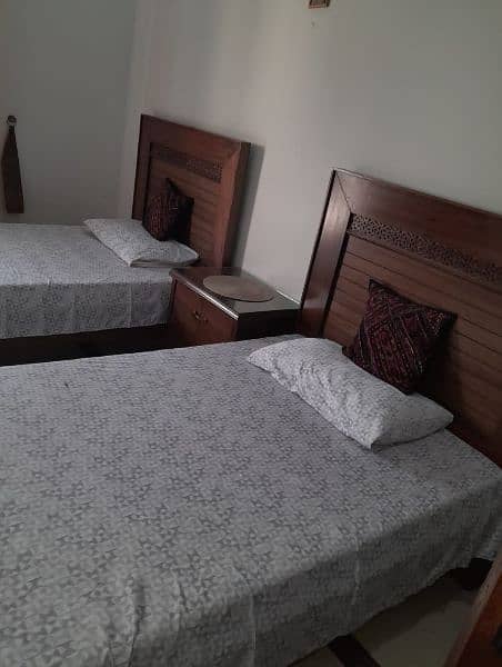 2 wooden single beds with 1 side table 2
