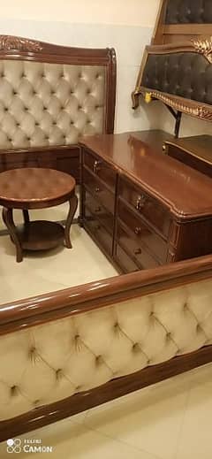 a double bed with two side tables and one dressing table.