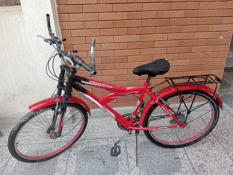 A well maintained red bicycle equipped with gears for sale 0