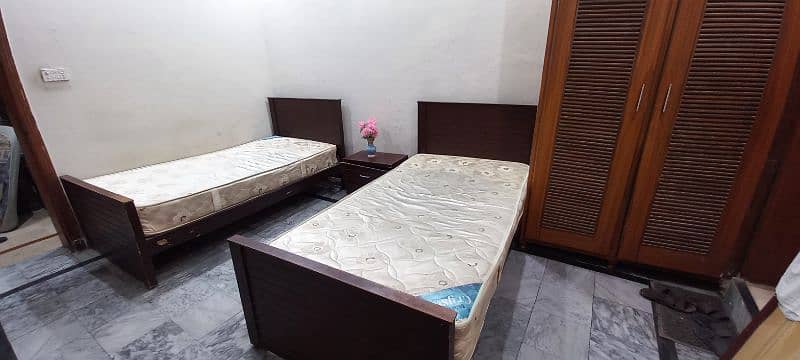 Single beds with spring mattresses and side table. 0