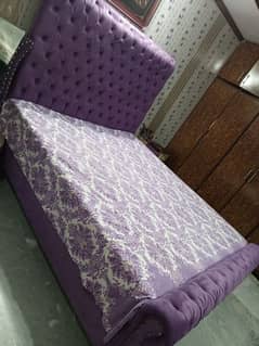 purple color velvet bed with side table and dresser