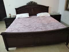 wooden bed with side table and mattress