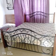 wrought iron bed with side tables and sofa with cousions