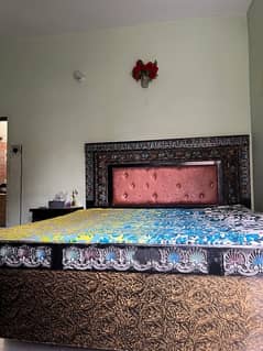 A bed with mattress alongside table for sale.