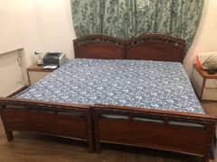 pair of single wooden beds with mattresses