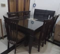 Dinning table with glass cover and 8 wooden chairs.