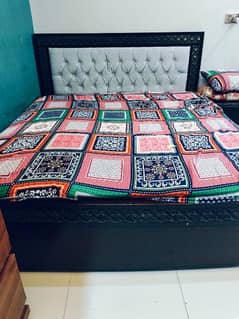 A wooden bed with spring mattress with 2 site tables