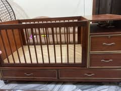 Baby cot / baby bed with mattress and storage capacity.