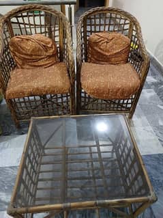 2 cane chairs with cushions/ cane table