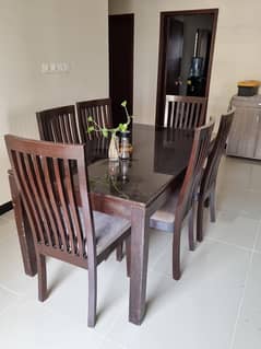 5 seater wood dining table with glass top and cushioned seats