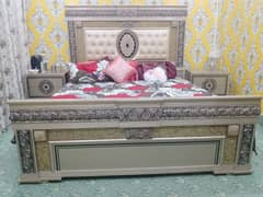 A bed with two sides tables and dressing table