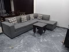 L shape sofa 7 seater. Grey colour with cushions and a table