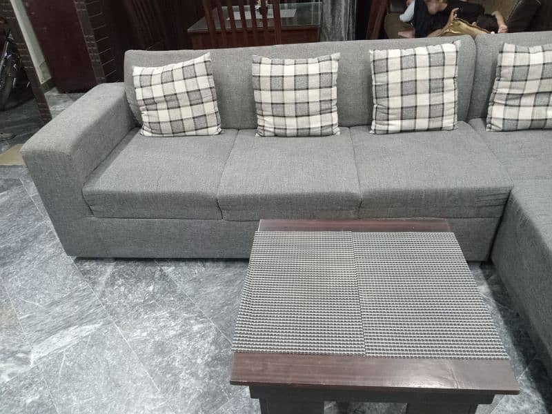 L shape sofa 7 seater. Grey colour with cushions and a table 1