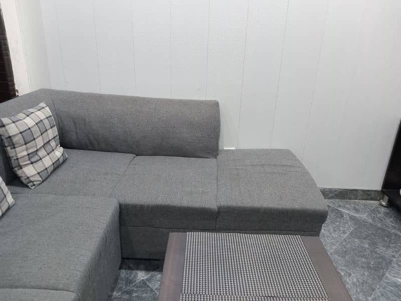 L shape sofa 7 seater. Grey colour with cushions and a table 4