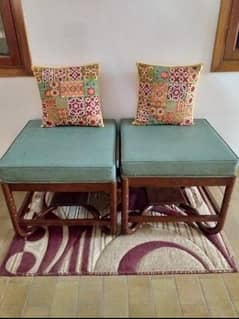 Green velvet ottoman with wooden frame.