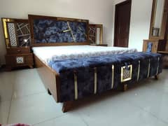 Queen size bed with side tables, storage sethi and a dressing table