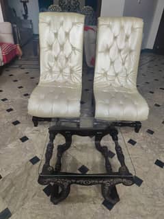 2 Hand Carved Room Chairs With A Glass Top Table.