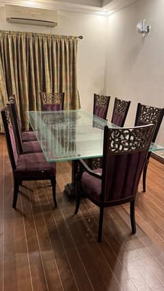 Glass table with wooden stylish , classical stand . 8 maroon chairs