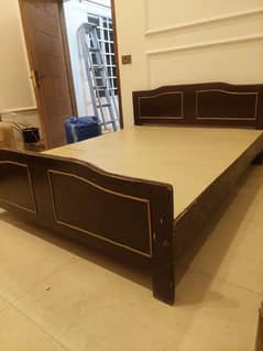 Wooden bed with a side table and dressing table not to old.