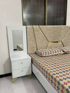 White bed set with side tables and vanity.