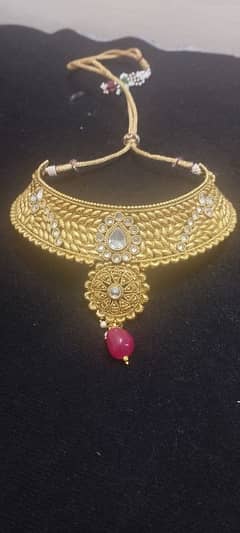 A golden red set and green earrings with bindiya