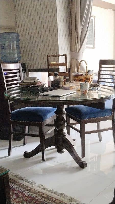 round dinning table with glass top with 4 beautiful chairs along 1