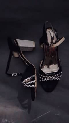 Black heel with silver pattern on it.