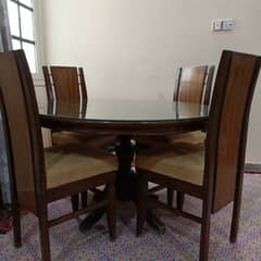 Round Dinning Table with 4 chairs. Glass placed over wooden top