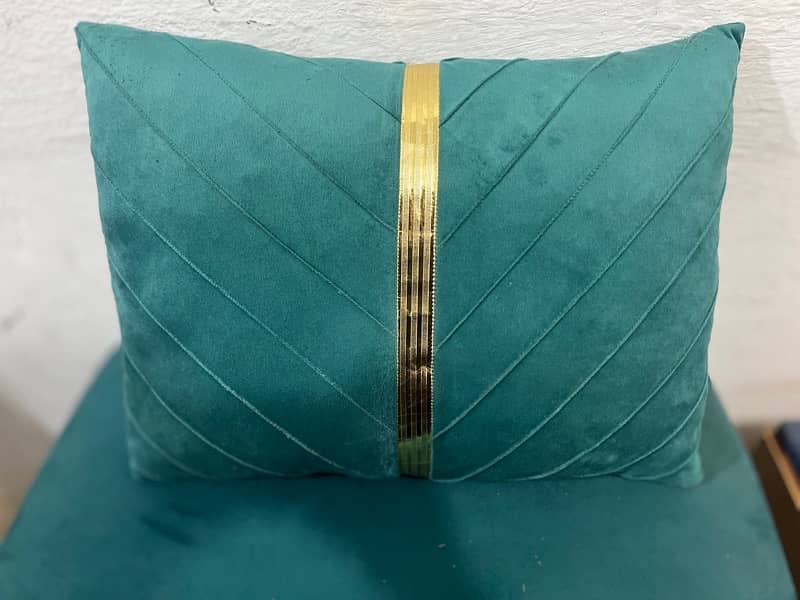 A rectangular teal velvet throw pillow with a vertical gold stripe 0