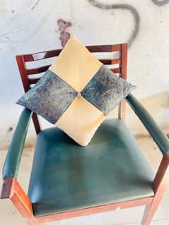 A beige and cream-green square cushion rests on a chair.