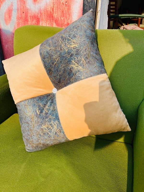 A beige and cream-green square cushion rests on a chair. 3