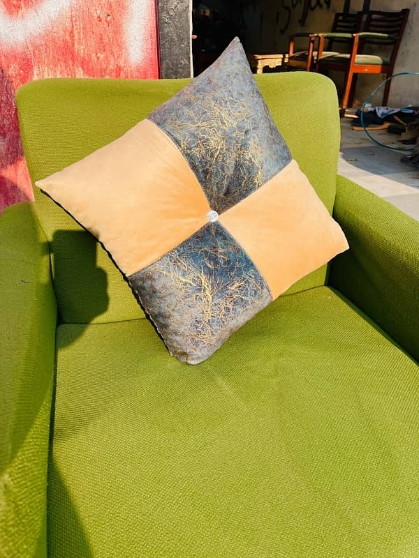 A beige and cream-green square cushion rests on a chair. 4