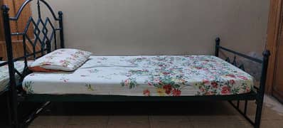 Two single iron beds with mattresses.