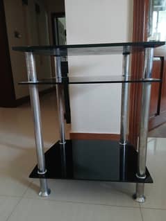 TV trolley with glass top and glass cabinets.