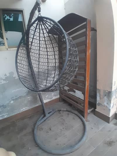 black single-seater iron and rattan egg swing chair with a stand