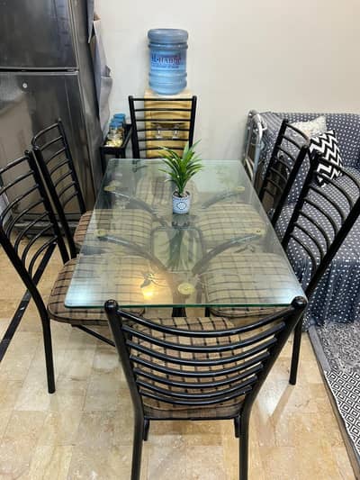 Iron dining table with glass top and six chairs.