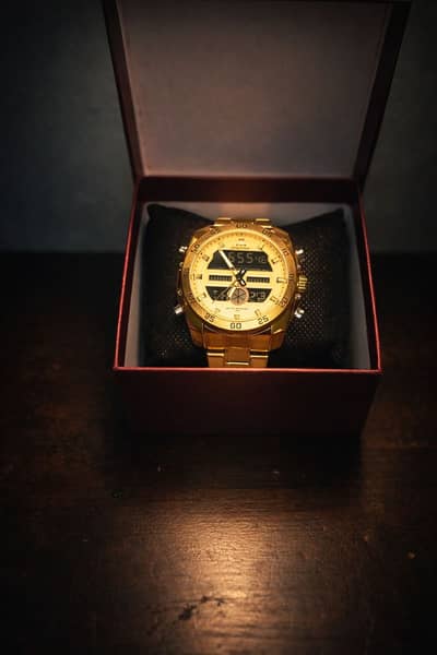 A GLODEN COLOR WATCH WITH 2 DIMENSIONS. A LIGHT TO SEE IN NIGHT.