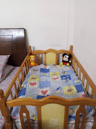 A cozy Baby cot with mattress in good condition and strong wood