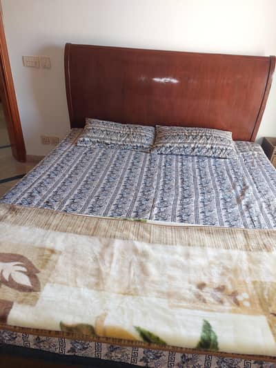 wooden King sized bed with dressing and side tables.