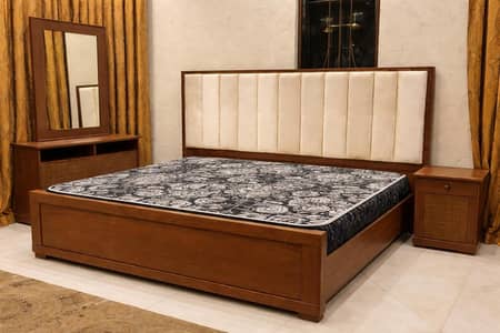 wooden bed with one side table and dressing table