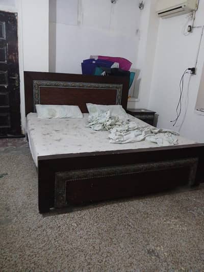 wooden bed with mattress, side table and dressing table