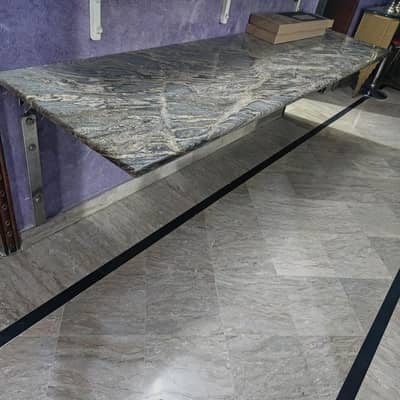 granite table with stainless steel fittings one side to walls