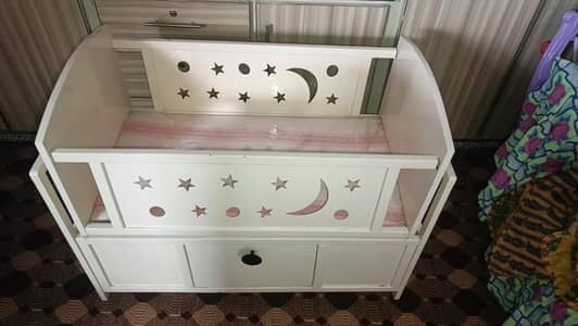 Baby cot with storage drawer.