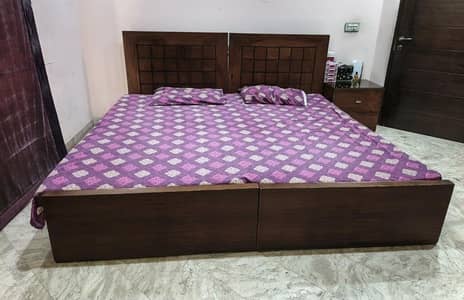 Two single beds with mattresses and one side table