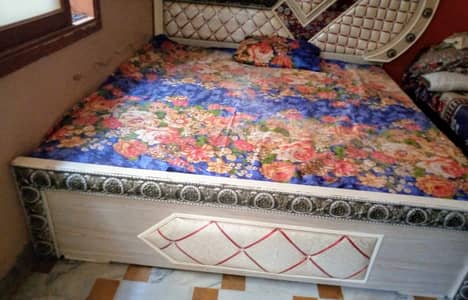 Double bed along with mattress and two side tables.