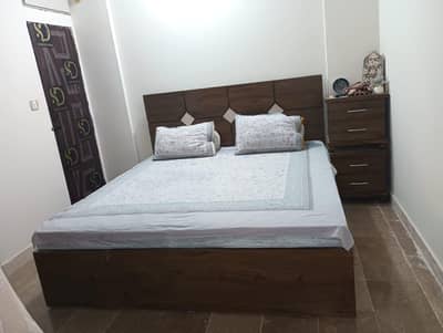 Wooden bed with mattress and side table.